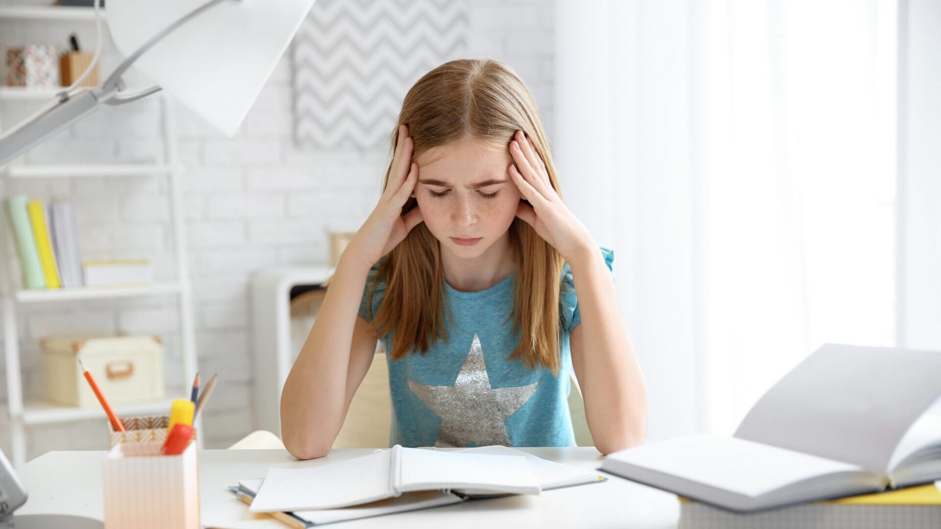 Teenage,Girl,Suffering,From,Headache,While,Doing,Homework,At,Table