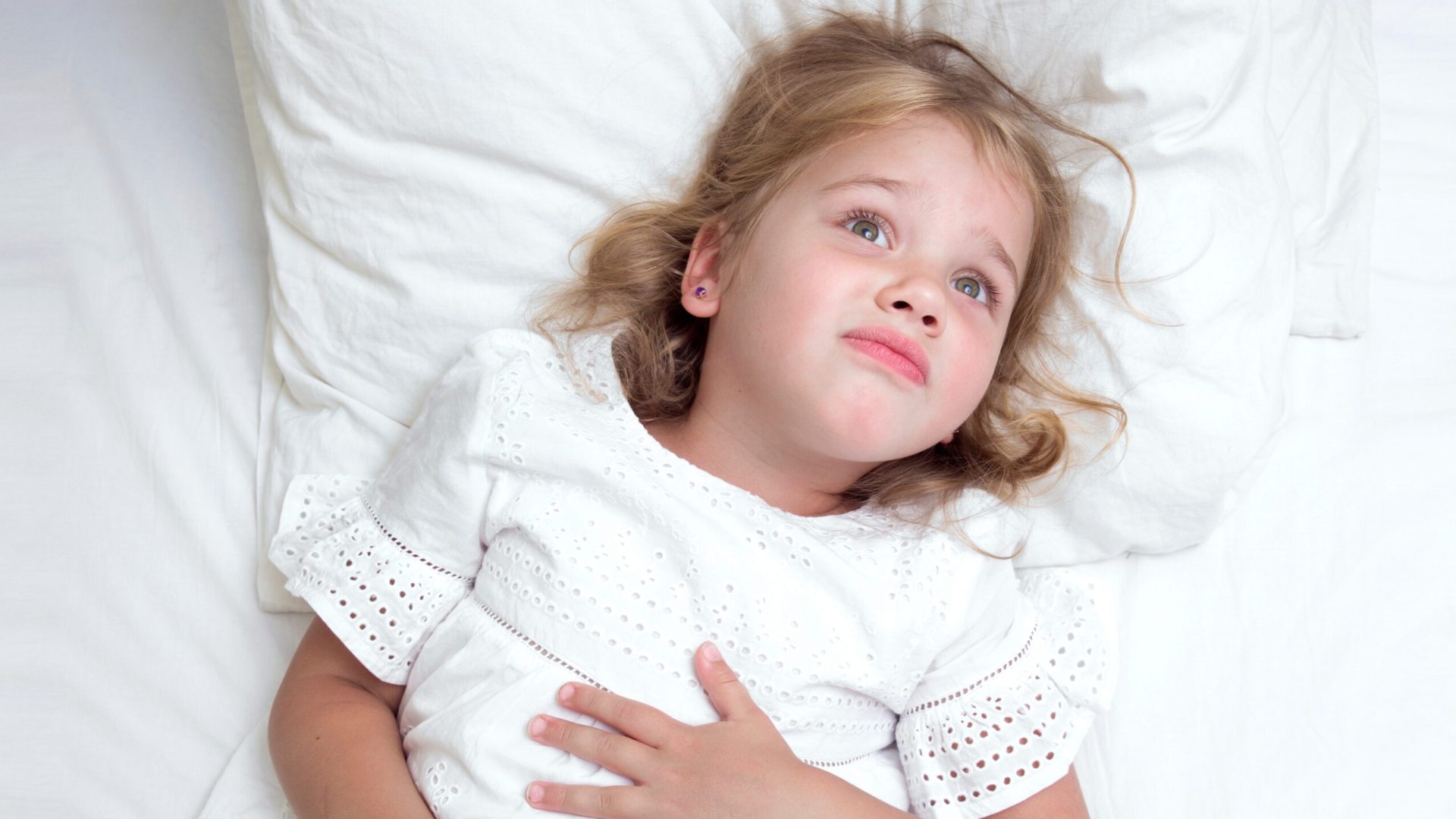 Child,Girl,In,Bed,With,Hands,On,Her,Stomach.,Caucasian