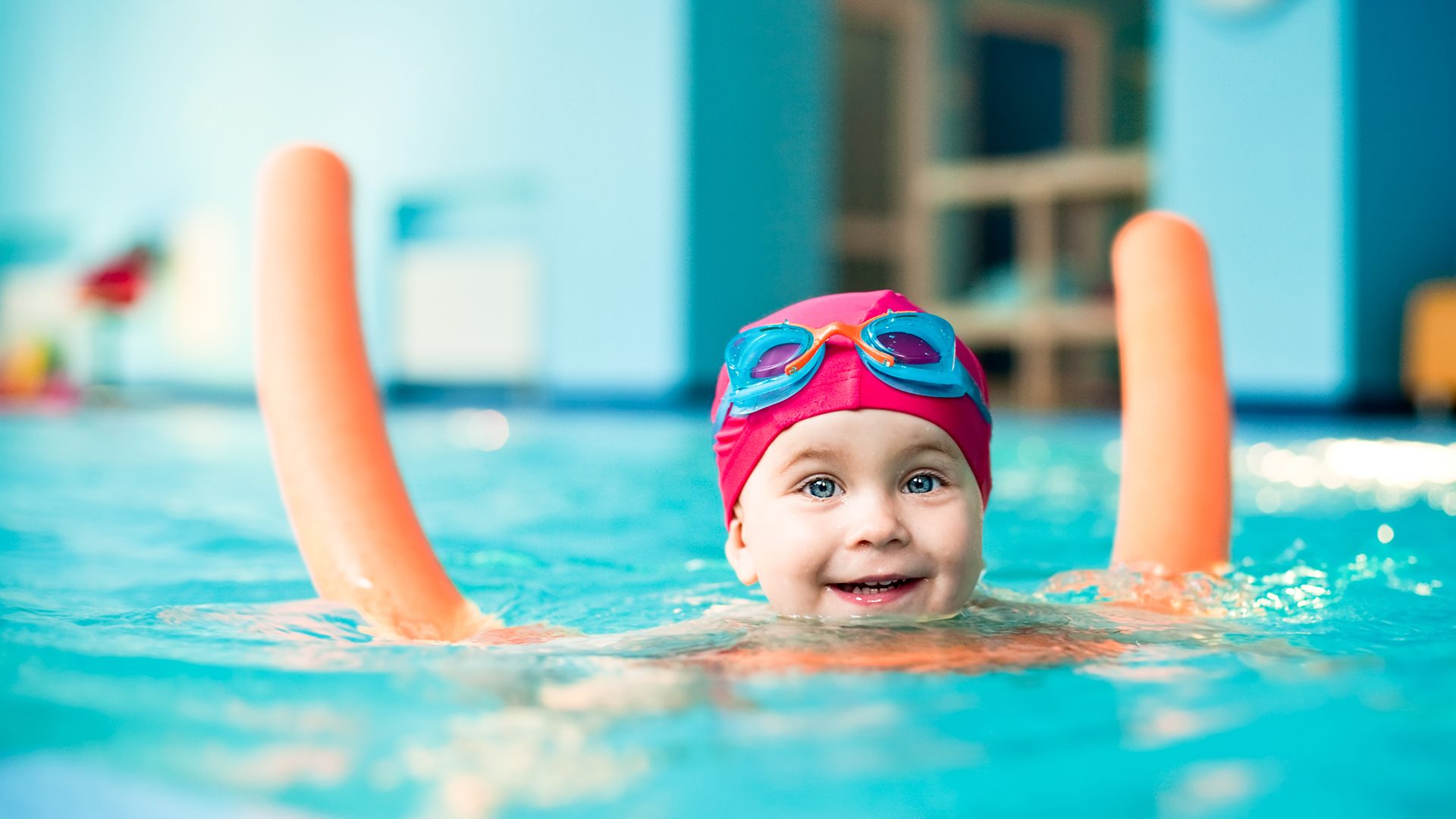 Happy little girl learning to swim with pool noodle